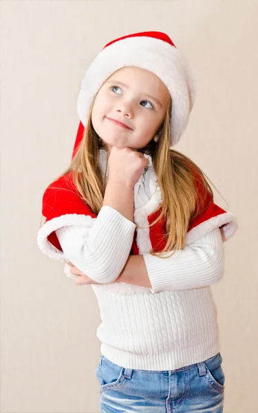 Feliz niña sonriente en sombrero de Navidad está soñando —  Fotos de Stock