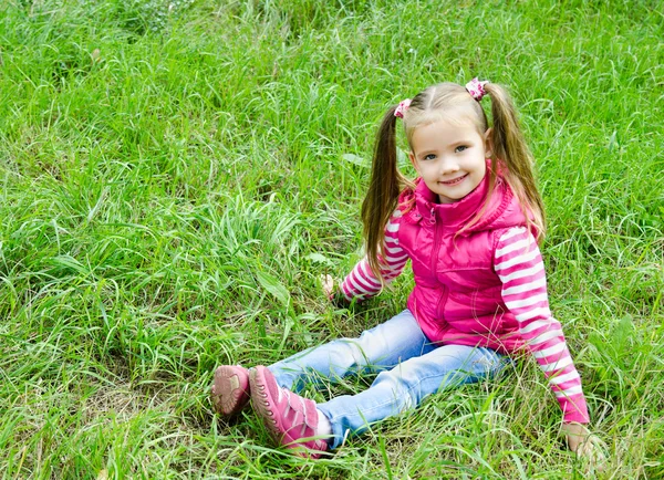 Carino sorridente bambina sdraiata in erba sul prato — Foto Stock