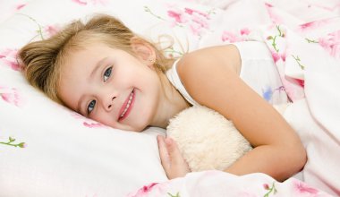 sevimli gülümseyen küçük kız yatağında waked