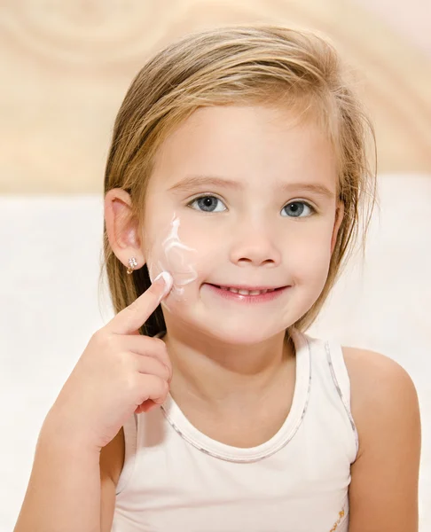 Cute little girl applying cream — Stock Photo, Image