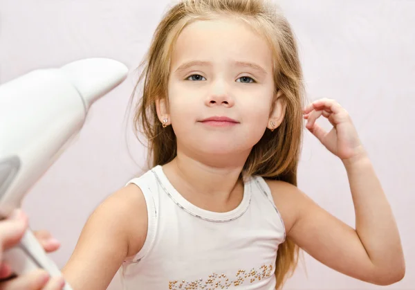 Niedlich lächelndes kleines Mädchen trocknet die Haare — Stockfoto