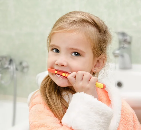 Smiling little girl brushing teeth in bath — Stock Photo, Image