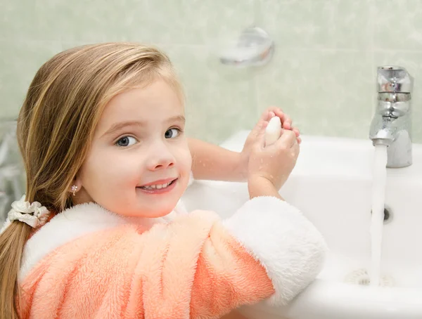 Улыбающаяся маленькая девочка моет руки в ванной — стоковое фото
