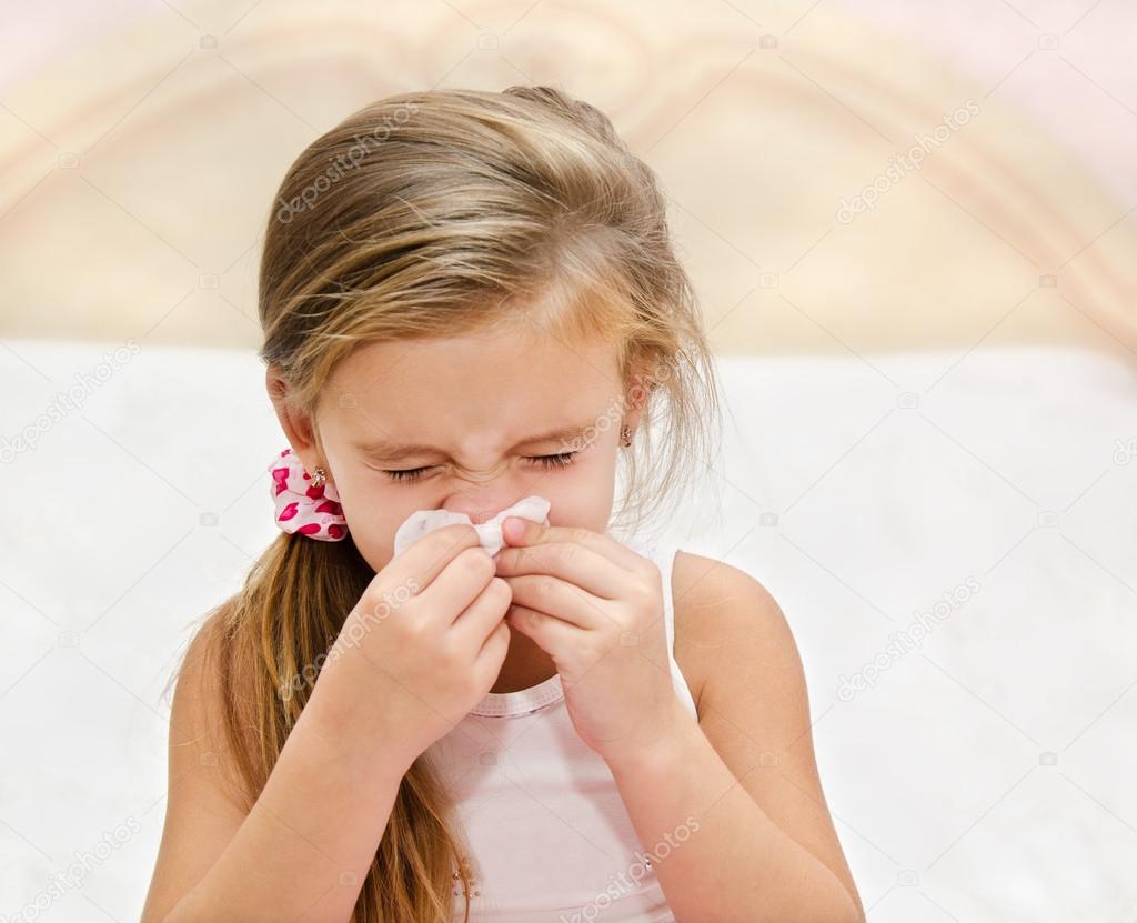 Little girl blowing her nose in a great effort