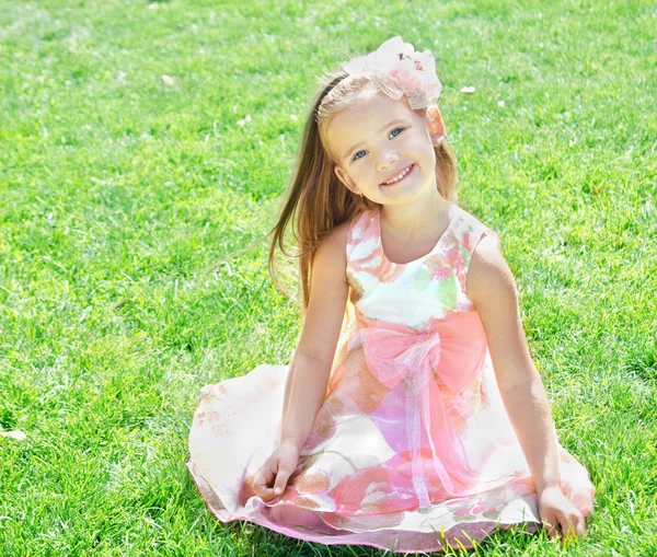 Adorável sorrindo menina sentada na grama — Fotografia de Stock