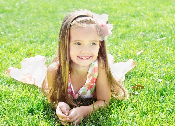 Roztomilý usměvavá holčička ležela na trávě — Stock fotografie