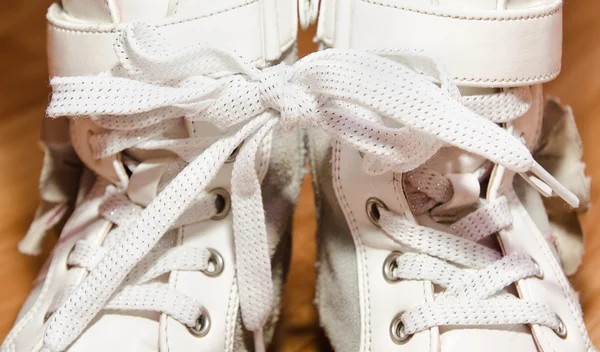 Pair of white leather girls shoes with laces tied together — Stock Photo, Image