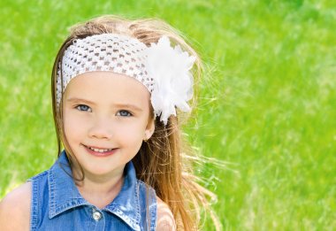 çayır üzerinde gülümseyen sevimli küçük kız portresi