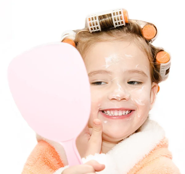 Glad söt liten flicka i Hårrullar tillämpa crea-spegel — Stockfoto