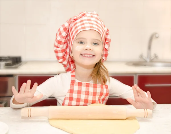 Smiling little girl with chef hat rolling dough — Stock Photo, Image