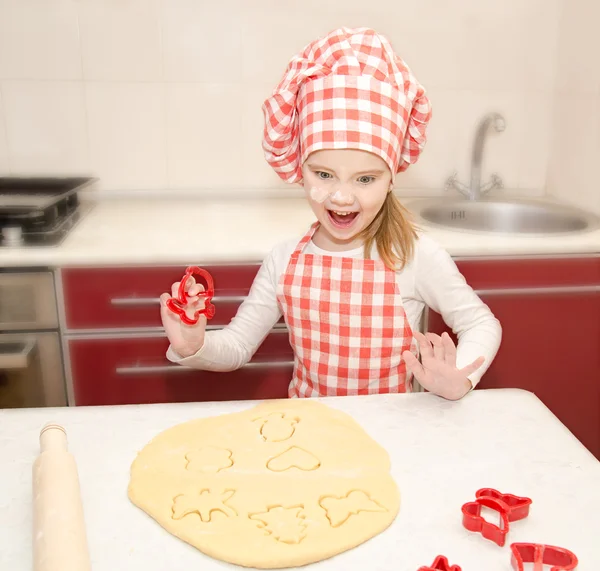 Glad liten flicka skär degen med form för cookies — Stockfoto