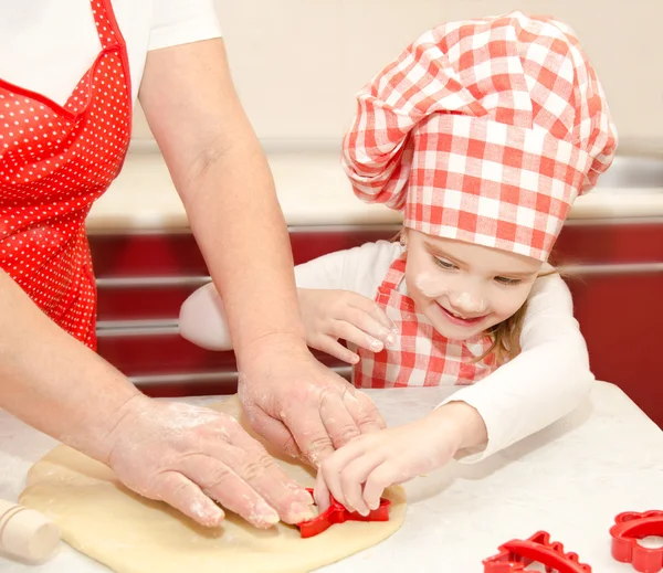Маленькая девочка и бабушка нарезали тесто с формой для печенья — стоковое фото