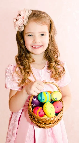 Linda niña sonriente con cesta llena de huevo de Pascua colorido — Foto de Stock