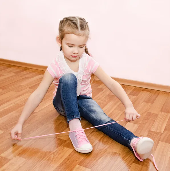 Милая маленькая девочка завязывает шнурки. — стоковое фото