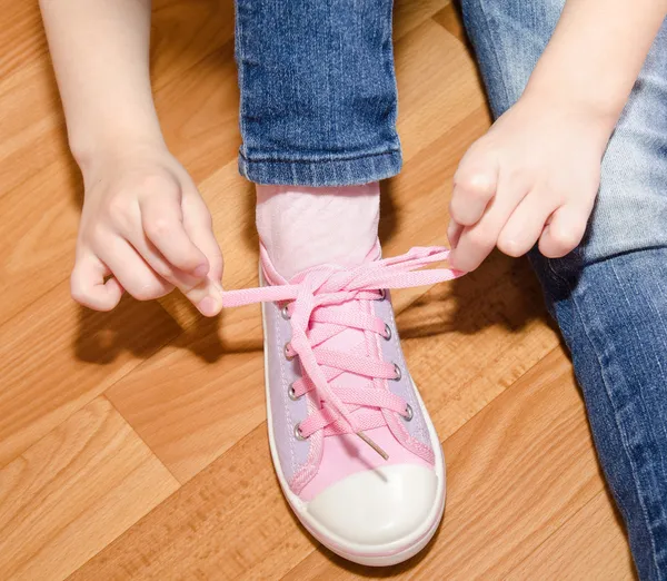 Barnet knyta hennes skor som sitter på golvet — Stockfoto