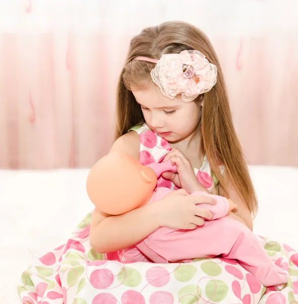 Carino sorridente bambina che gioca con una bambola — Foto Stock