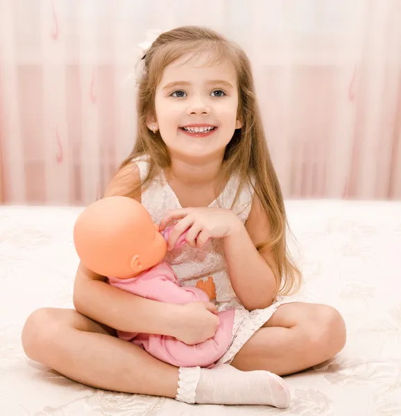 Carino sorridente bambina che gioca con una bambola — Foto Stock