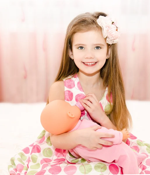 Petite fille souriante mignonne jouant avec une poupée — Photo