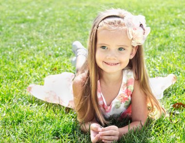 sevimli gülümseyen küçük kız çim üzerinde yalan