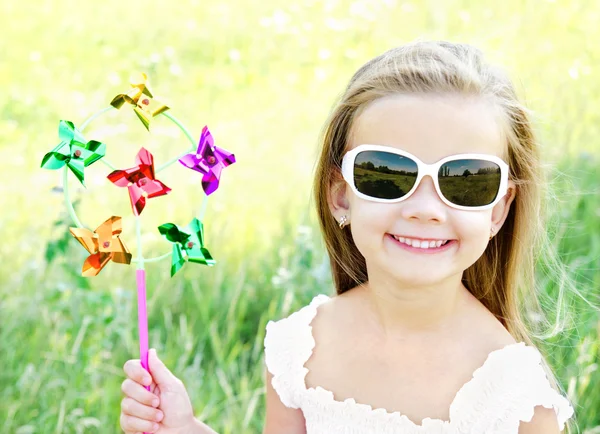 Lachende meisje spelen met windmolen speelgoed buiten — Stockfoto