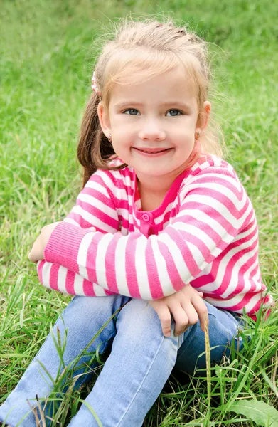 Retrato de adorable niña sonriente sentada en la hierba —  Fotos de Stock