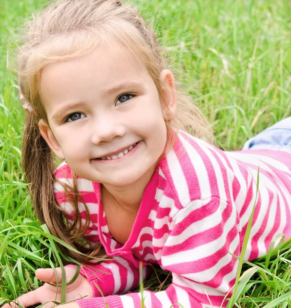 Portre sevimli gülümseyen küçük kız çim üzerinde yalan — Stok fotoğraf