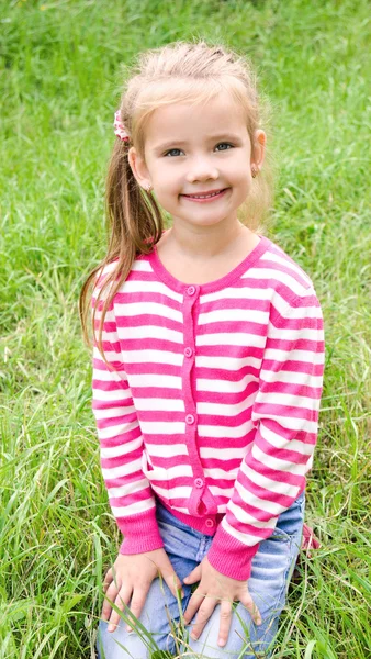 Portrait of adorable smiling little girl sitting on grass — Stock Photo, Image