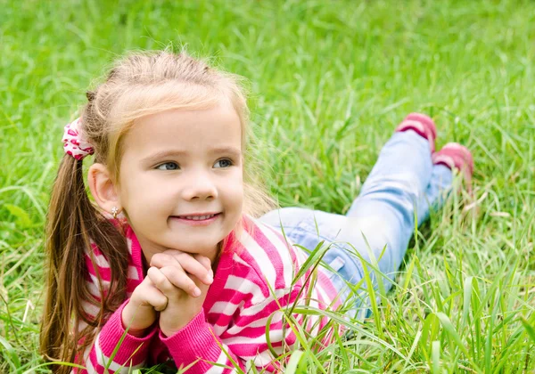 Porträtt av bedårande leende liten flicka liggande på gräs — Stockfoto