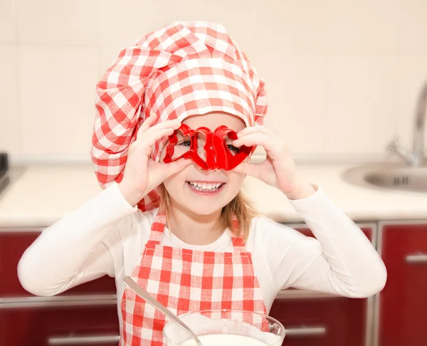 Glückliches kleines Mädchen hat Spaß mit Form für Plätzchen in Kochmütze — Stockfoto