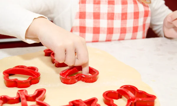 Маленькая девочка режет тесто с формой для печенья на кухне — стоковое фото