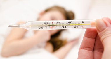  holding termometre ön planda ve hasta bir küçük kız anne