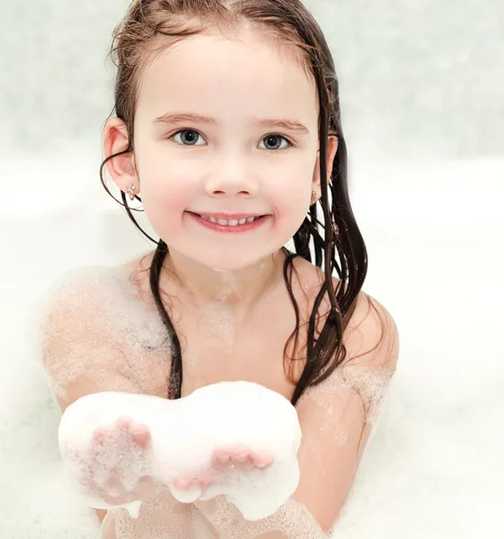 Leende liten flicka tvätt i badet med skum — Stockfoto