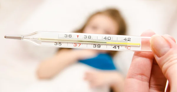 Madre sosteniendo el termómetro en primer plano y niña enferma — Foto de Stock