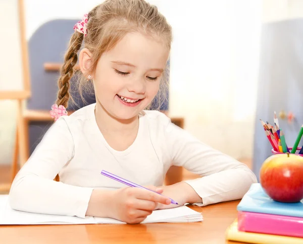 Is het schrijven van schattig klein meisje aan de balie in voorschoolse — Stockfoto