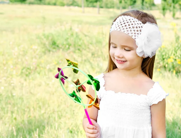 Smiling little girl playing with windmill toy — Stock Photo, Image
