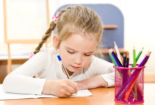 La niña está escribiendo en el escritorio en preescolar. —  Fotos de Stock