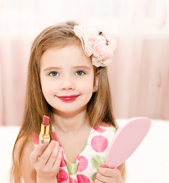 Linda niña con lápiz labial y espejo — Foto de Stock