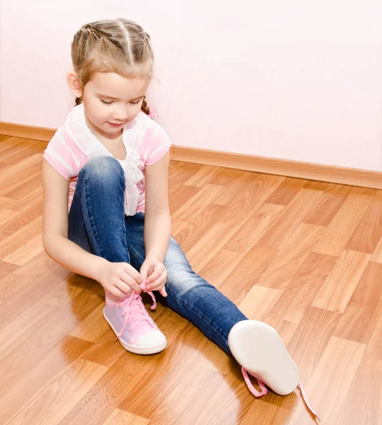 Schattig klein meisje koppelverkoop haar schoenen — Stockfoto