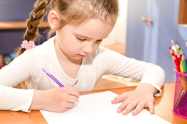 Nettes kleines Mädchen schreibt am Schreibtisch — Stockfoto