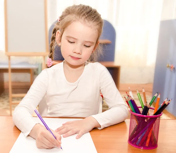 Sevimli küçük kız masa başında yazma — Stok fotoğraf