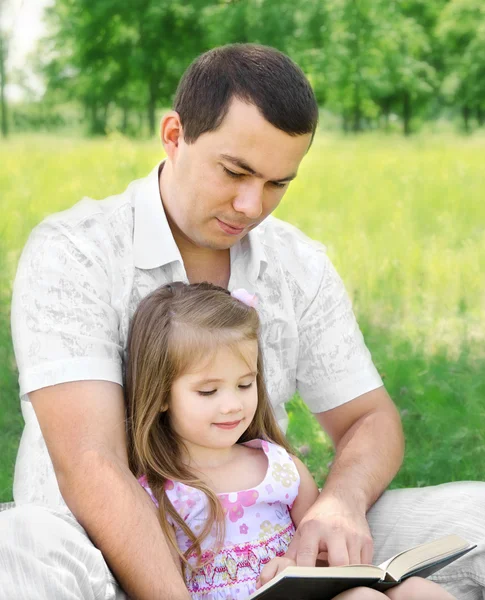 Padre con hija leyendo en el parque — Foto de Stock