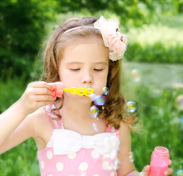 Schattig klein meisje blaast een zeepbel — Stockfoto