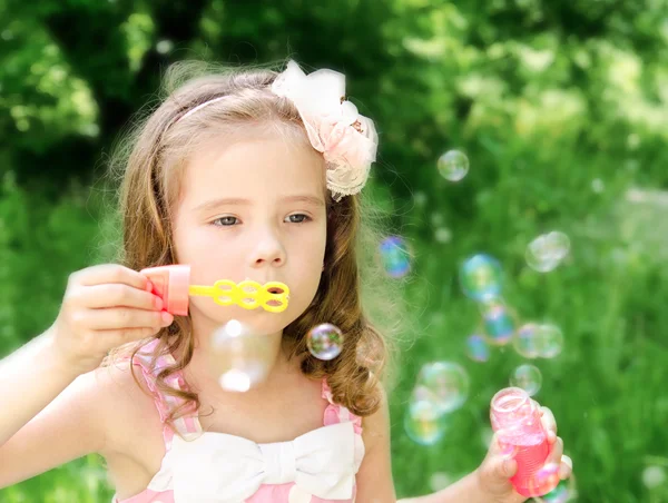 Schattig klein meisje blaast een zeepbel — Stockfoto