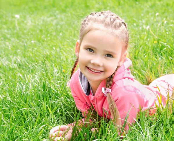 Portrait of adorable smiling little girl lying on grass — Stock Photo, Image