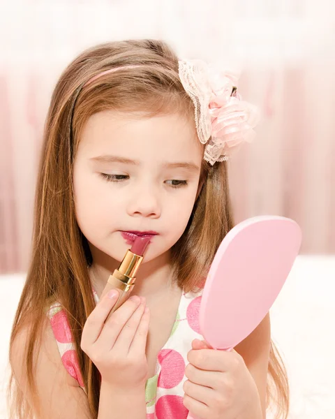 Schattig klein meisje met lippenstift en spiegel — Stockfoto