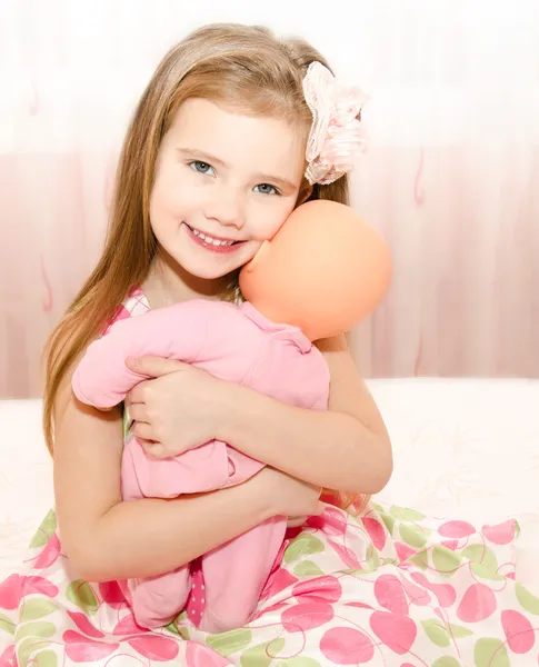 Очаровательная улыбающаяся девочка, играющая с куклой — стоковое фото