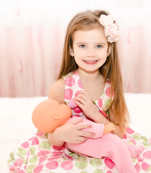 Милая улыбающаяся девочка, играющая с куклой — стоковое фото