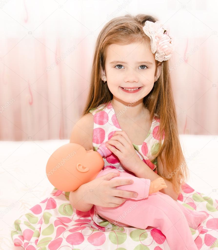 Cute smiling little girl playing with a doll