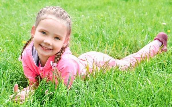 Retrato de adorável sorridente menina deitada na grama — Fotografia de Stock