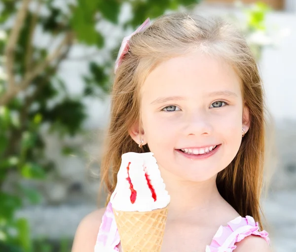 Очаровательная улыбающаяся маленькая девочка ест мороженое — стоковое фото
